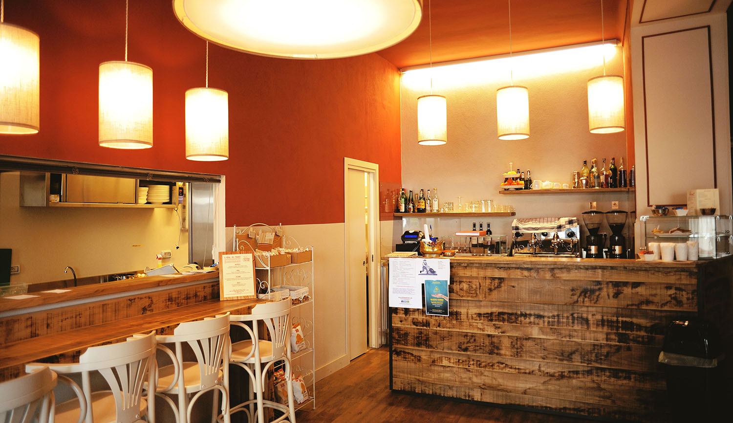 Il bancone in legno del bar, con lampade a sospensione e muro color terracotta